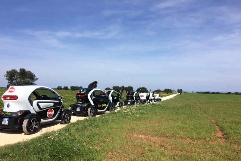 Elektrische Mini-Autos zwischen Olivenbäumen und Weizenfeldern in Apulien